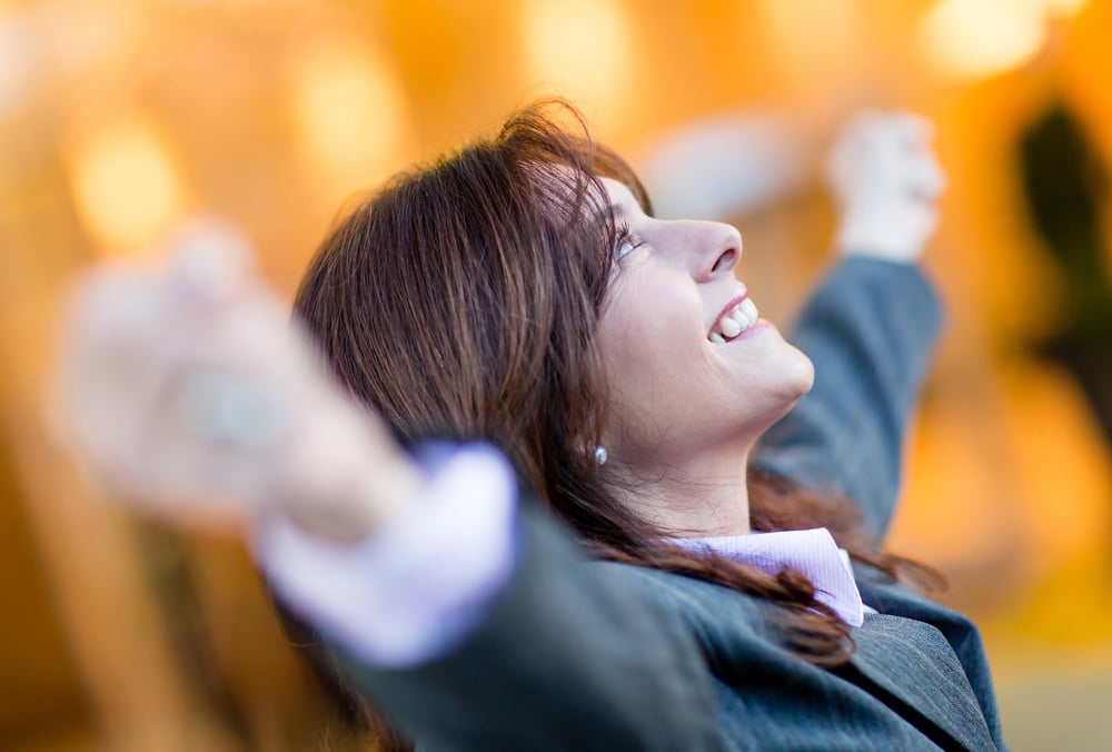 Successful business woman celebrating with arms open